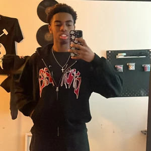 Svart hoodie med röd tryck från Weekday - Svart hoodie från Weekday med fet röd och vit grafisk tryck på bröstet. Tröjan har huva med snörning, dragkedja framtill och långärmade ärmar. Passformen är loose och materialet är mjuk bomull. Perfekt för dig som gillar streetwear och vill sticka ut.  Ny pris 600kr. Kontakta för fler frågor