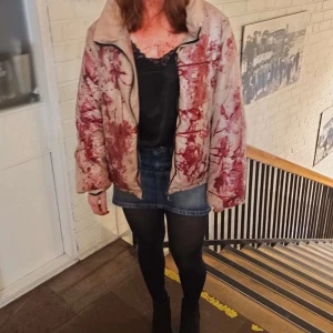 Jennifer’s body dunjacka - Dunjacka med fejkblod på, jag använde den till min Jennifer Check-kostym på halloween men man kan ju ha den till någon annan kostym om man vill. Blodet har jag gjort och dränkt jackan med, kan tvättas bort (jag kan göra det åt dig om du vill). Jackan är inte helt vit utan mer beige. OBS blodet beter sig lite konstigt, om man är i kontakt med en yta länge så kan den lämna lite kladd typ, men den kladdar inte på kläder eller hud. Och allt går att tvätta bort med lite vatten. Skriv för fler bilder.