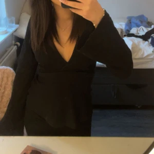 Svart omlottopp med v-ringning - Säljer en svart omlottopp med djup v-ringning och långa, vida ärmar. Toppen har en figurnära passform upptill och faller snyggt över midjan. Perfekt för dig som gillar stilrena och trendiga plagg. Storlek xxs ifrån Gina tricot pris går att diskuteras 
