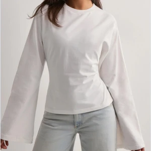 Vit långärmad topp med öppen rygg från Nelly - Säljer en vit långärmad topp från Nelly med öppen rygg och snygg knytning bak. Toppen har vida ärmar och är tillverkad i mjuk bomull. Perfekt för dig som vill ha en stilren men ändå unik look. Helt ny med prislapp kvar! Nypris 299kr 💕