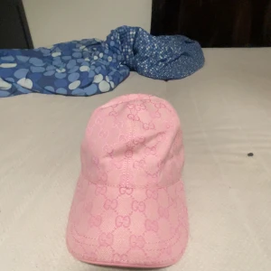 Rosa Gucci keps med monogram - Säljer en rosa keps från Gucci med klassiskt GG-monogram över hela kepsen. Kepsen har böjd skärm, justerbar rem bak och är tillverkad i ett slitstarkt tyg. Perfekt för dig som vill sticka ut med en lyxig och trendig accessoar.