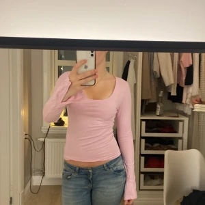 Ljusrosa långärmad topp med fyrkantig ringning - Säljer en ljusrosa långärmad topp med snygg fyrkantig ringning. Modellen är tight och croppad, perfekt att styla med jeans eller kjol. Tunt och mjukt material som känns skönt mot huden. Enkel men trendig design som passar till många olika looks.