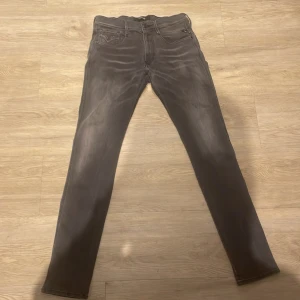 Replay Anbass mörkgrå jeans - Snygga Replay Anbass jeans i mörkgrå tvätt med klassisk femficksdesign och smal passform. Jeansen har dragkedja och knapp i midjan. Materialet är stretchigt jeans för extra komfort. Perfekt för dig som gillar stilrena och moderna jeans. Skick 9/10