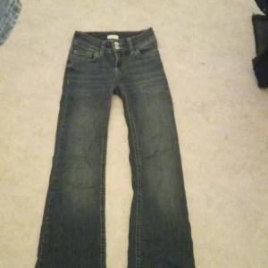 Bootcut jeans från Nelly med broderi - Snygga mörkblå bootcut jeans från Nelly med coolt broderat mönster på bakfickorna. Klassisk femficksmodell med knappstängning och bälteshällor.  Storlek 32 jag har använt dom 3 gånger och tvättat en gång aldrig har åkt torktumlare!!!!