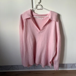 Ljusrosa stickad tröja med krage - Supermjuk ljusrosa stickad tröja från lager 157 med bred krage och v-ringning. Tröjan har lång ärm och ribbade muddar vid ärmslut och nederkant. Perfekt för lager-på-lager och chill dagar.