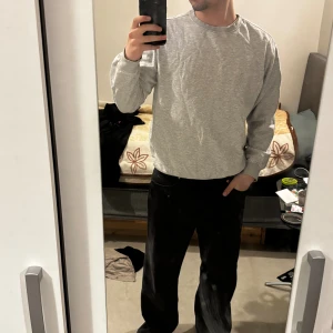 Grå sweatshirt från H&M Relaxed Fit - En stilren grå sweatshirt från H&M i relaxed fit. Tröjan har rund halsringning, långa ärmar och ribbade muddar vid ärmslut och nederkant. Perfekt för en chill och avslappnad look. Tillverkad i mjuk bomullsblandning för extra komfort. Storlek S men passar även storlek M