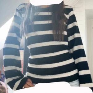 Svartvit randig stickad tröja - Säljer en svart och vit randig stickad tröja med lång utsvängd ärm. Tröjan har en rund halsringning och är i en mjuk, skön kvalitet som passar perfekt till jeans eller kjol. Snygg och enkel att styla för en fin höst dag🍁 Den är i storlek M, jag har sytt om den så den är tightare i midjan så skulle säga S. 