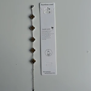 Green-silver Alhambra bracelet - Snyggt armband i rostfritt stål med fem fyrklöverformade länkar i brunt och silver. Varje länk har ett randigt mönster och är omgiven av små silverpärlor. Perfekt för dig som gillar unika detaljer och stilren design. Mvh clover.se