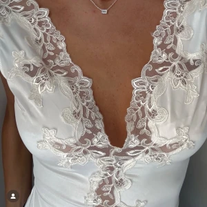 Vit spetsbody med djup v-ringning - Supersnygg vit body i satin med djup v-ringning och detaljerad spets med blommigt mönster längs halsen och bröstet. Helt slutsåld på Zaras hemsida 🩷