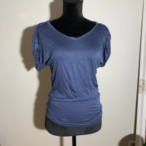 Blå topp med v-ringning - Mjuk o luftig t-shirt från Gina. Längd ca 65cm. Pris: 10kr