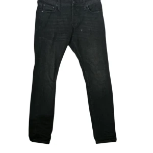Svarta slim jeans från Jack & Jones  - Svarta slim jeans från Jack & Jones med klassisk femficksdesign och diskreta sömmar. Jeansen har en smal passform och är tillverkade i stretchigt denim för extra komfort. Perfekta för dig som gillar en stilren och enkel look.