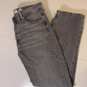 Grå jeans från Jack & Jones - Snygga grå jeans från Jack & Jones med klassisk femficksdesign och raka ben. Jeansen är tillverkade i mjukt bomullsmaterial. Perfekta för dig som gillar en enkel och clean look.                          Storlek: 34/32