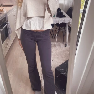 Mörkgrå bootcut byxor låg midja - Snygga mörkgrå bootcut byxor låg midja och stretchigt material. Byxorna har en figurnära passform upptill och utsvängda ben, vilket ger en trendig siluett.