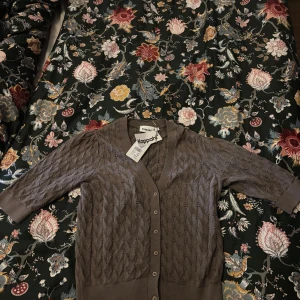 Brun stickad kofta från Kappahl - Supersöt brun stickad kofta från Kappahl med fina hålmönster och knappar framtill. Köpt för 399🩷