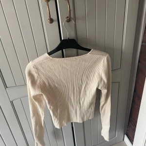 Ribbad beige långärmad topp Gina Tricot - Säljer en ribbad långärmad topp från Gina Tricot i beige. Toppen har en snygg fyrkantig urringning och är croppad i modellen. Perfekt att styla med jeans eller kjol för en trendig look.