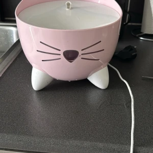 Katt fontän - Söt luftfuktare eller vattenfontän i form av en rosa katt med vita tassar. Elektrisk med sladd, passar perfekt för barnrum eller som dekoration. Ser ut att vara i gott skick utan synliga skador eller slitage.