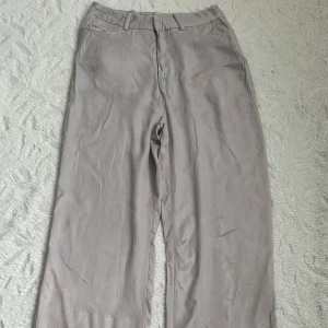 Ljusgrå vida satinbyxor från Zara - Snygga ljusgrå satinbyxor från Zara i storlek XS. Vida ben och hög midja. Gjorda i ett mjukt, lätt material som känns skönt mot huden. Supersnygga på, skriv för flera bilder 🥰