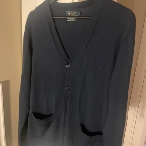 🤍 Riley marinoull kofta (strl S) - Elegant marinblå kofta från Riley, storlek S.   Tillverkad i mjuk och varm marinoull – perfekt för kyliga dagar.   Detaljer som två framfickor, tre knappar och diskret Riley-logga ger en tidlös och stilren look.  ✨ Skick: Mycket bra – knappt använd, inga defekter eller noppor.   📏 Storlek: S (normal passform)   📦 Skickas snabbt och välpaketerat!  💰 Pris: 449kr (en klassiker i garderoben som håller år efter år!)