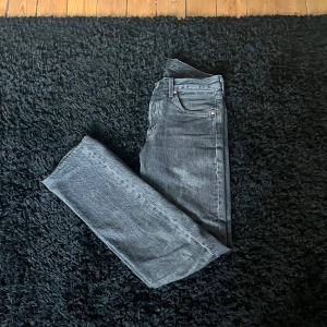 Levi's 501 grå jeans W28 L32 - Säljer ett par klassiska Levi's 501 jeans i snygg grå tvätt. Modellen har rak passform, fem fickor och knappgylf. Jeansen är tillverkade i slitstarkt bomullsjeansmaterial och har den ikoniska läderpatchen bak i midjan. Kan gå ner i pris vid snabb affär!! 