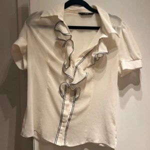 Vit blus med volang från F&F - Skjortan är lite genomskinlig som man kan se på bilden men väldigt fin. Man knäpper den hela vägen och sen är det volang vid bröstet 
