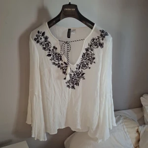 Vit blus med broderi från H&M Divided - Supersöt vit blus från H&M Divided med svart broderat blommönster längs v-ringningen. 💞