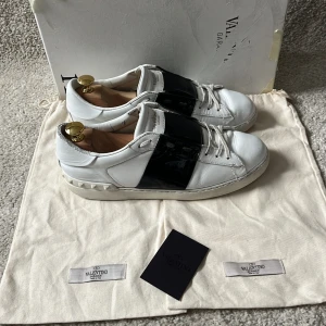 Valentino open skor - Valentino Garavani Open skor! Box, 2st dustbags och kort medföljer vid köp av skorna!  Skick: fint skick annars men slitna på sulan och inuti. Färg: vita skor med svart lackerad rand. Nypris: 8500kr. Mitt pris är endast 1600kr!