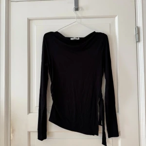 Svart topp från NAKD - Topp från Nakd. Storlek S. Använd en gång. Båtringad med lite drapering. Knyt i sidan, scrunched på andra sidan. Stretchig. Köpt för 349kr
