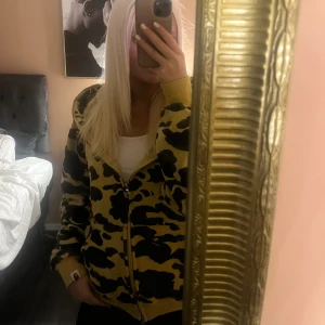 BAPE camo hoodie med dragkedja - Säljer hoodiefrån BAPE som är köpt på big Apple i Malmö med  gul och svart camouflage-mönster.