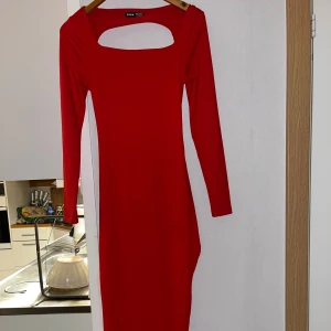 Röd långärmad klänning från SHEIN - Röd långärmad klänning från SHEIN med fyrkantig cut-out vid halsen och öppen rygg med knytband. Jag har sytt om urringningen till en mer fyrkantig form, vilket inte syns tydligt. Klänningen är figurnära och har en längre passform. Perfekt för dig som vill sticka ut med en snygg och trendig look. Perfekt inför julen ❤️