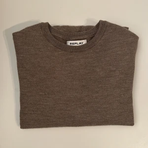Beige stickad tröja från Replay - Snygg beige stickad tröja från Replay med rund halsringning, diskret logga och ribbade muddar