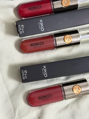 KIKO Unlimited Double Touch läppfärger - Säljer tre KIKO Unlimited Double Touch Liquid Lip Colour i nyanserna 108, 132 och 133. Färgerna är olika röda toner, från klassiskt röd till varm terrakotta. Varje tub är 6 ml och har en stilren design med guld- och svartdetaljer samt genomskinligt lock.