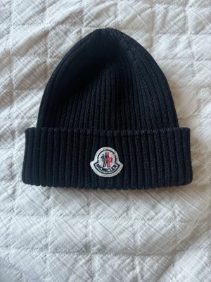 Moncler mössa - Jättesnygg moncler mössa som är sparsamt använd! Säljer pågrund av att den inte riktigt är min stil längre💕Köptes på NK Göteborg 2021! Nypris 2500kr! Pris går att diskutera 