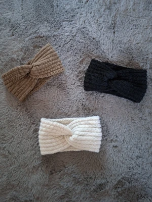 Stickade pannband beige, svart och vit  - Tre stickade pannband i ribbad design, en i beige, en i svart och en i vit. Panbanden har en twistad detalj framtill som ger en cool look. Perfekt att ha på sig en kall vinterdag för extra stilpoäng och varma öron.
