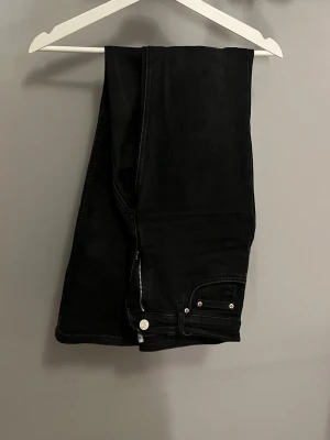 Svarta jeans från Gina tricot , strl 40 - Säljer ett par svarta jeans från Gina i storlek 40. . Jeansen har en ”flare” benform och är tillverkade i mjukt denimtyg som sitter snyggt och bekvämt.