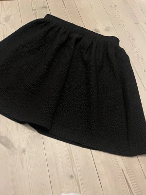 Svart kortkjol från Monki, stl 36 - Säljer en svart kortkjol från Monki i storlek 36..