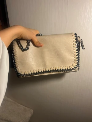 Beige axelväska med kedja - Säljer en beige axelväska med coola metallkedjor.