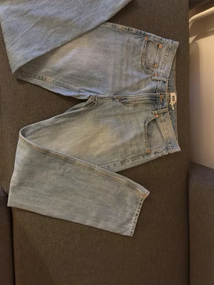 Ljusblå jeans från 151, W32 L32 - Säljer ett par ljusblå jeans från 151 i klassisk femficksmodell. Jeansen har raka ben och normal passform, med snygga kontrastsömmar och läderpatch bak i midjan. Perfekt för dig som gillar enkel och tidlös denimstil.