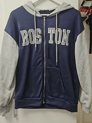 Hoodie - Cool Boston hoodie i grå och blå. Använd max 2 gånger och har bara hängt i min garderob så dags att sälja. Storlek S men kan säkert passa M också.