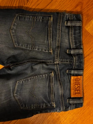 Diesel blå slim skinny jeans 10Y - Snygga blå jeans från Diesel i modellen Sleenker-J-N, slim skinny fit med stretch. Klassisk femficksdesign, markerade sömmar och läderpatch med Diesel-logga bak. Perfekt passform för dig som gillar smalare jeans med lite attityd.