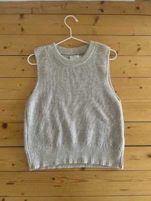 Beige stickad väst från ONLY - Säljer en beige stickad väst från ONLY i storlek XS. Västen har en rund halsringning och breda ribbade kanter vid hals och nederkant. Perfekt att styla över en skjorta eller t-shirt🩵