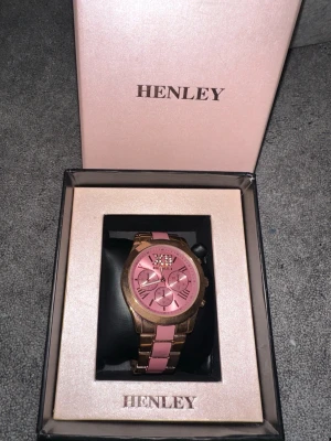 Henley klocka  - En rosa och guld Henley-klocka i presentförpackning, fint skick men för stor för mig och behöver justeras vilket jag inte gjort.