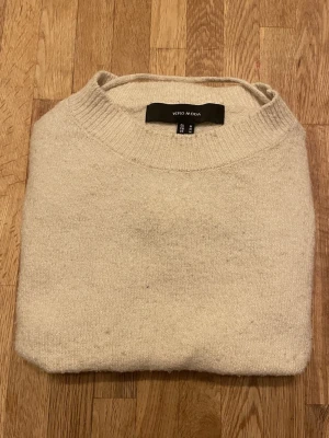 Beige stickad tröja Vero Moda  - Mysig beige stickad tröja från Vero Moda i storlek M. Tröjan har rund hals och puffade trekvartsärmar med breda muddar. Perfekt för kyliga dagar och enkel att matcha med jeans eller kjol.