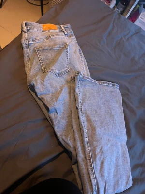 Ljusblåa jeans - Säljer ett par ljusblåa jeans från Vero Moda. De är i bra skick men kan ha någon tråd men inget som påverkar användningen. Storlek M/32 midjemått: 38cm rakt över. Innerbens längd: 80cm. nypris: 599kr