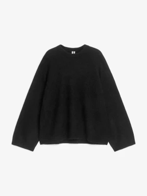 Svart stickad tröja med rund hals - Mysig svart stickad tröja med rund halsringning och långa ärmar. Tröjan har en enkel, clean look och är lätt oversized. Alpacka- och ullblandning. Nypris är 1000kr
