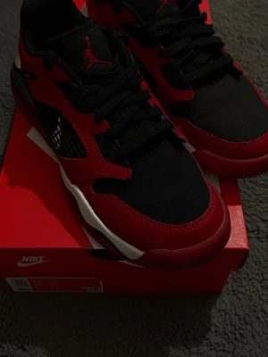 Nike Jordan Mars 270 sneakers röd/svart - Nike Jordan Mars 270 sneakers i rött och svart med vita detaljer. Skorna har meshpaneler, snörning och en synlig Air Max-sula. Jumpman-logga på plösen och hälen, samt Mars-etikett på sidan. Kombination av skinn och syntetmaterial för en sportig vibe.