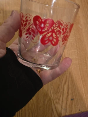 Röd hjärtmönstrad IKEA-glas - Säljer ett glas från IKEA med ett gulligt rött hjärtmönster runt hela kanten. Glaset är tillverkat i Frankrike och har en klassisk rund form. 