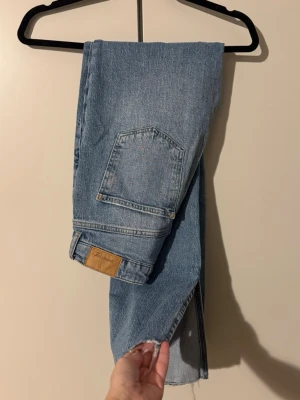Ljusblå jeans med slits från Gina Tricot  - Ljusblå raka jeans från Gina, fransig kant nedtill. Jeansen har hög midja och är tillverkade i slitstarkt bomullsdenim. Perfekta för en chill och avslappnad stil. Snygg slits längst ned. Endast testade! 
