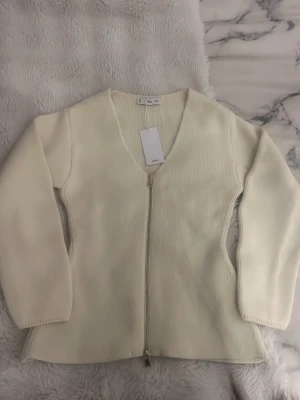 Beige stickad  - Snygg beige stickad kofta från mango med v-ringning och hel dragkedja framtill i guld. Den är tillverkad av ull, akryl och poliamid. Lite kroppssydd som ger en clean och stilren look. Perfekt att slänga på sig när det är lite kyligt ute, köpt för 499. Den har aldrig använts. Lappen kvar. Pris går att diskuteras 💞💞