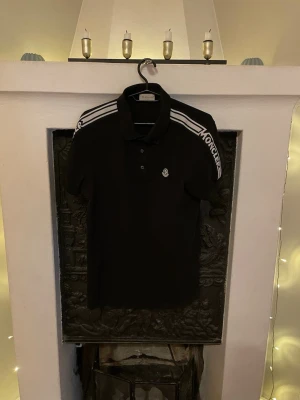Svart Moncler pikéskjorta med logga - Svart och vit moncler piké, lappar och original påse ingår. Riktigt fet piké helt enkelt men säljs pga behöver pengar. 