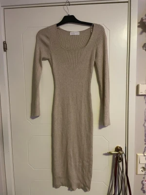 Beige ribbad långklänning Samsa - Snygg beige långklänning från Samsa Collection i storlek S. Klänningen är ribbad, har långärmade och en djup v-ringad hals. Materialet är stickat och ger en skön och slim passform som framhäver figuren. Perfekt för dig som gillar stilrena och enkla plagg. Nypris 300:-